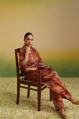 Woman wearing rust printed farshi salwar set with embroidered neckline and dupatta, sitting view
