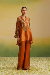 Woman wearing rust paisley printed asymmetric coord set with wide-leg pants