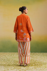back view of Woman wearing orange floral printed tissue kurta with striped farshi salwar